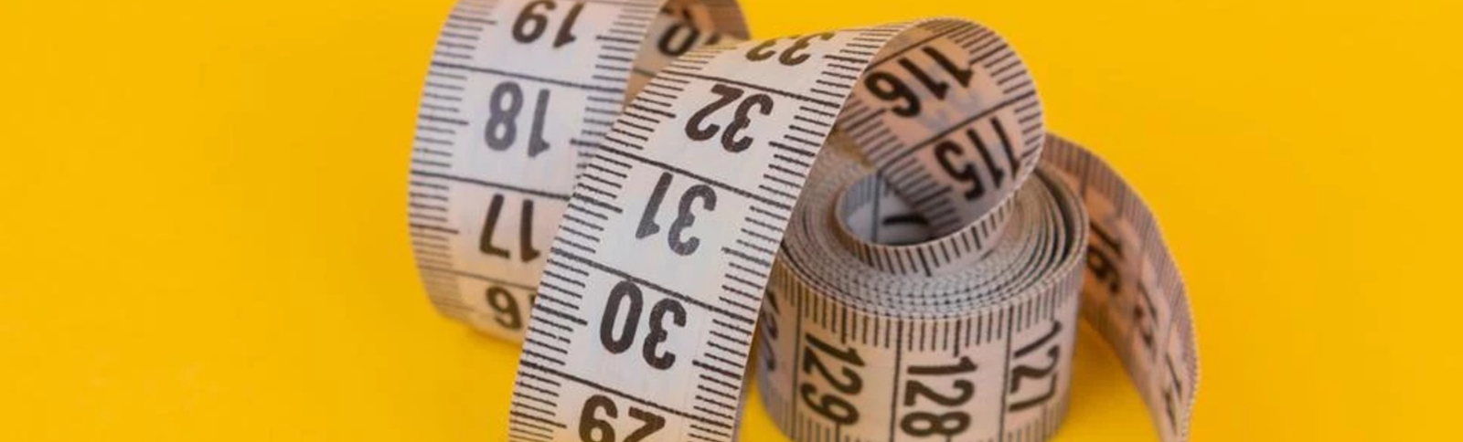 A yellow background with a measuring tape, signifying structured metrics and data tracking for corporate talent strategy ROI.
